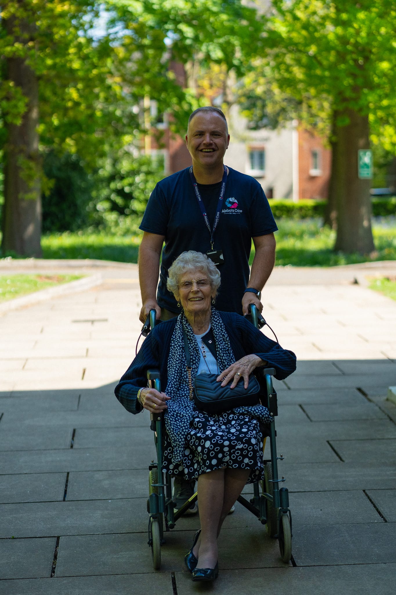Care Worker Paul pictured pushing a client in a wheelchair along on a warm summer's day