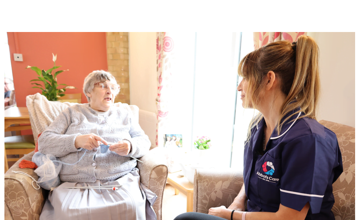 A Care Worker talks to a client whilst they knit