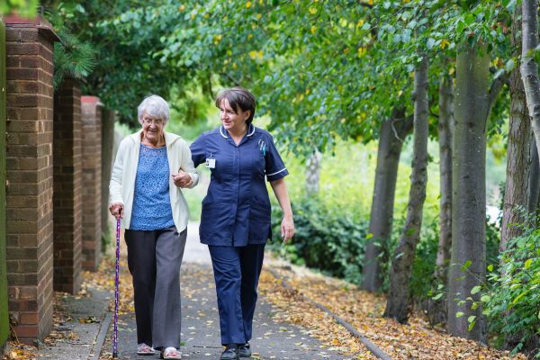 Care Worker and elderly client walking in a park