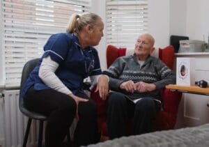 A live-in Abbots Care Worker Maggie sits with client in their home.