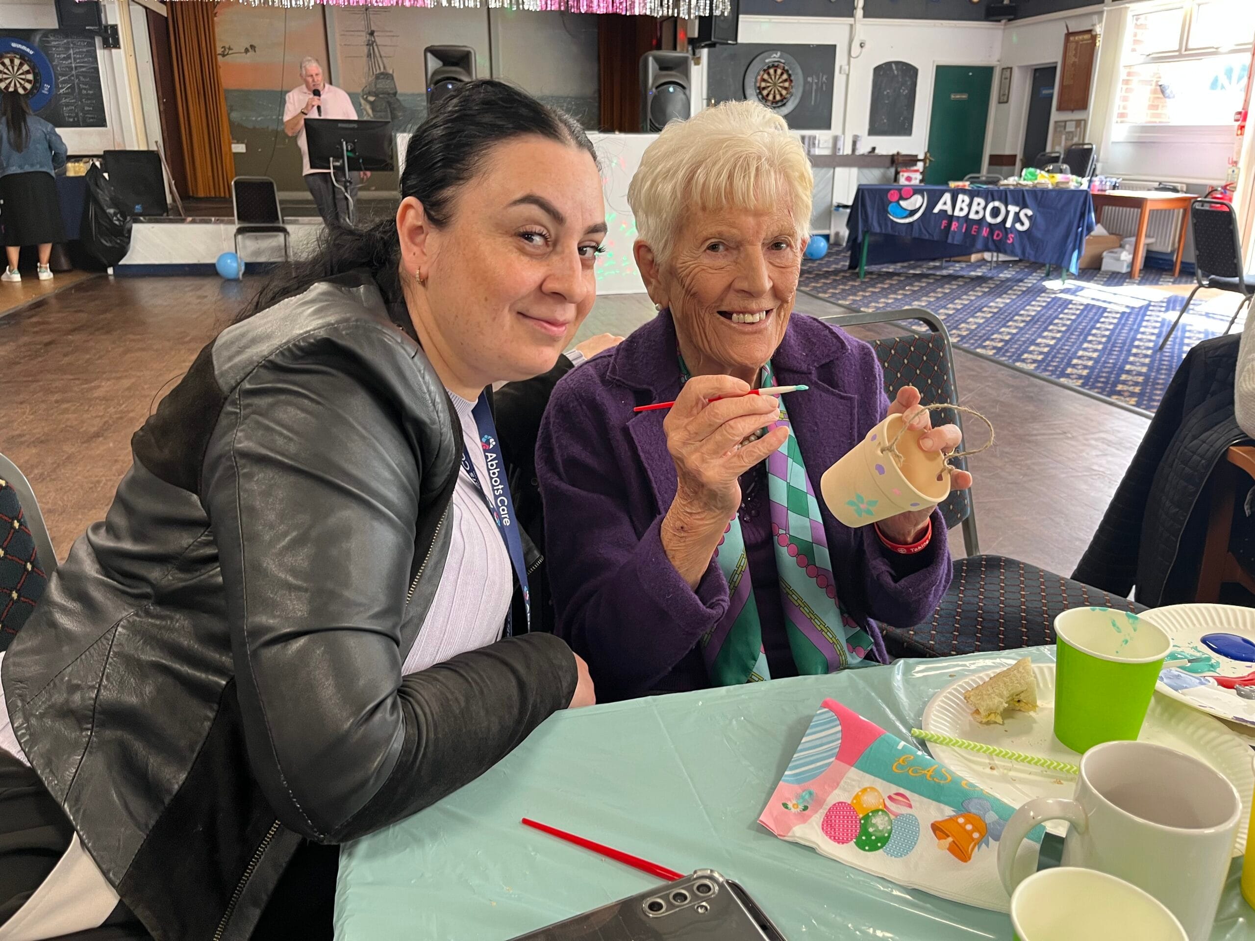 A Care Worker and client pictured simling while completing some arrts and crafts at an Abbots Care tea party