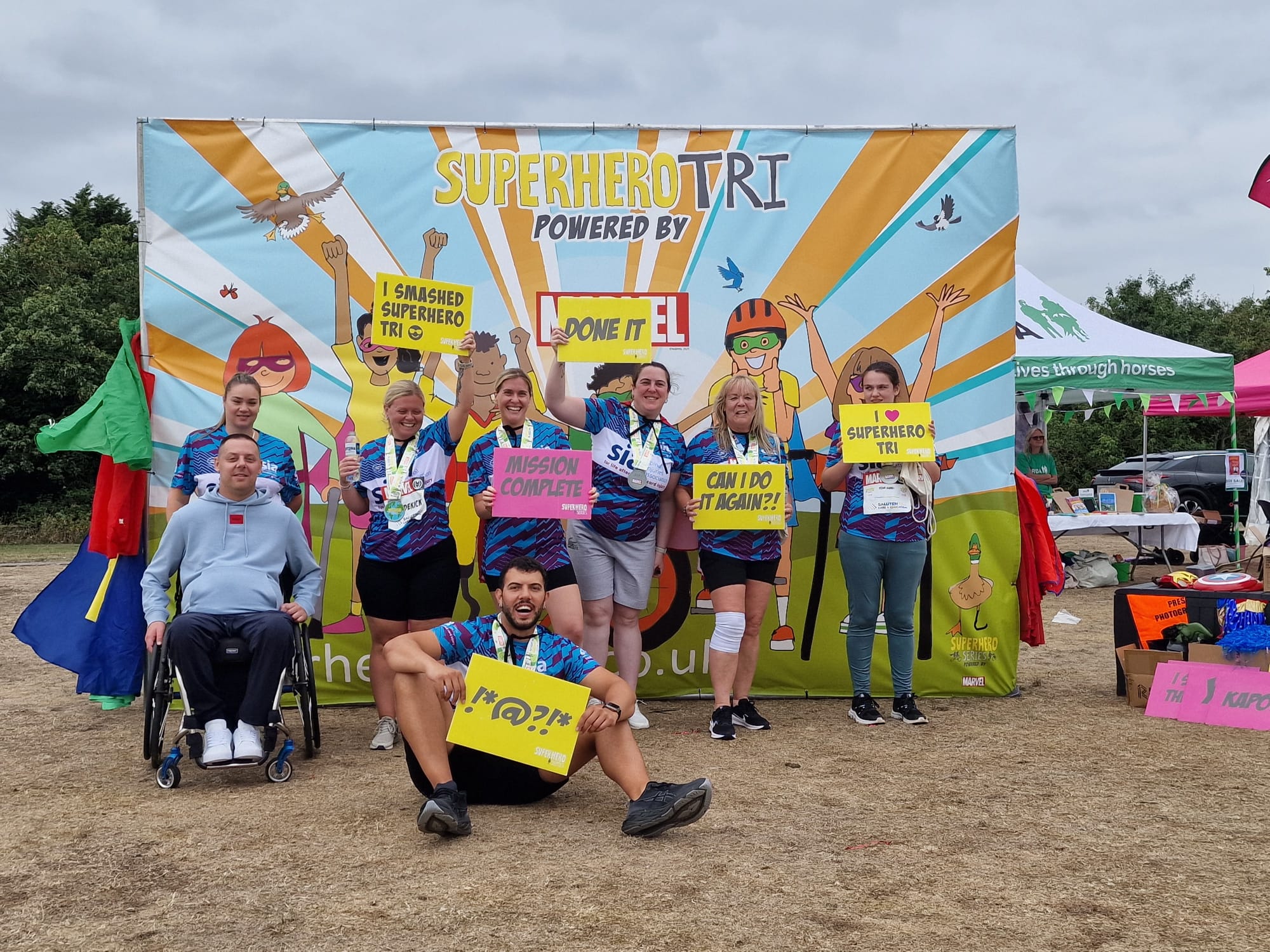 Group of Abbots Care team members smiling at the finish line of the Superhero Triathlon