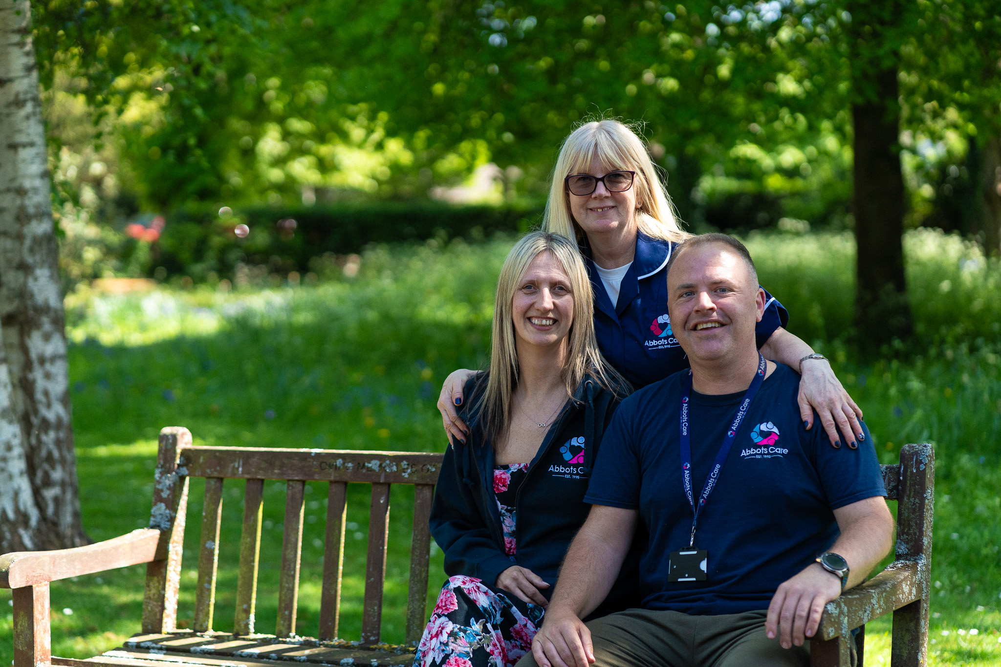 Three Abbots Care Workers pictured on a bench on a warm summer's day
