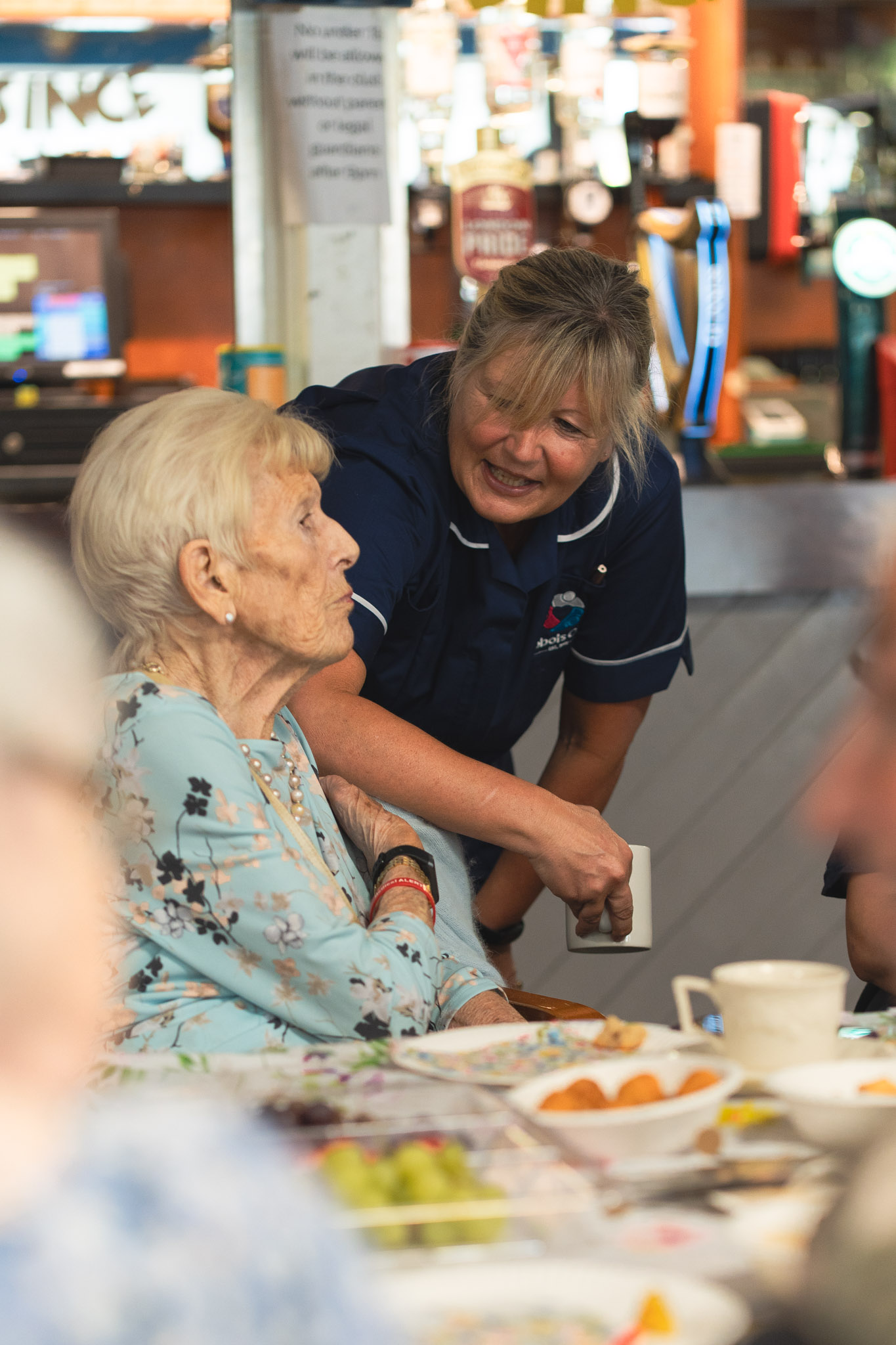 A Care Worker and an elderly female client chat at an Abbots Care tea party